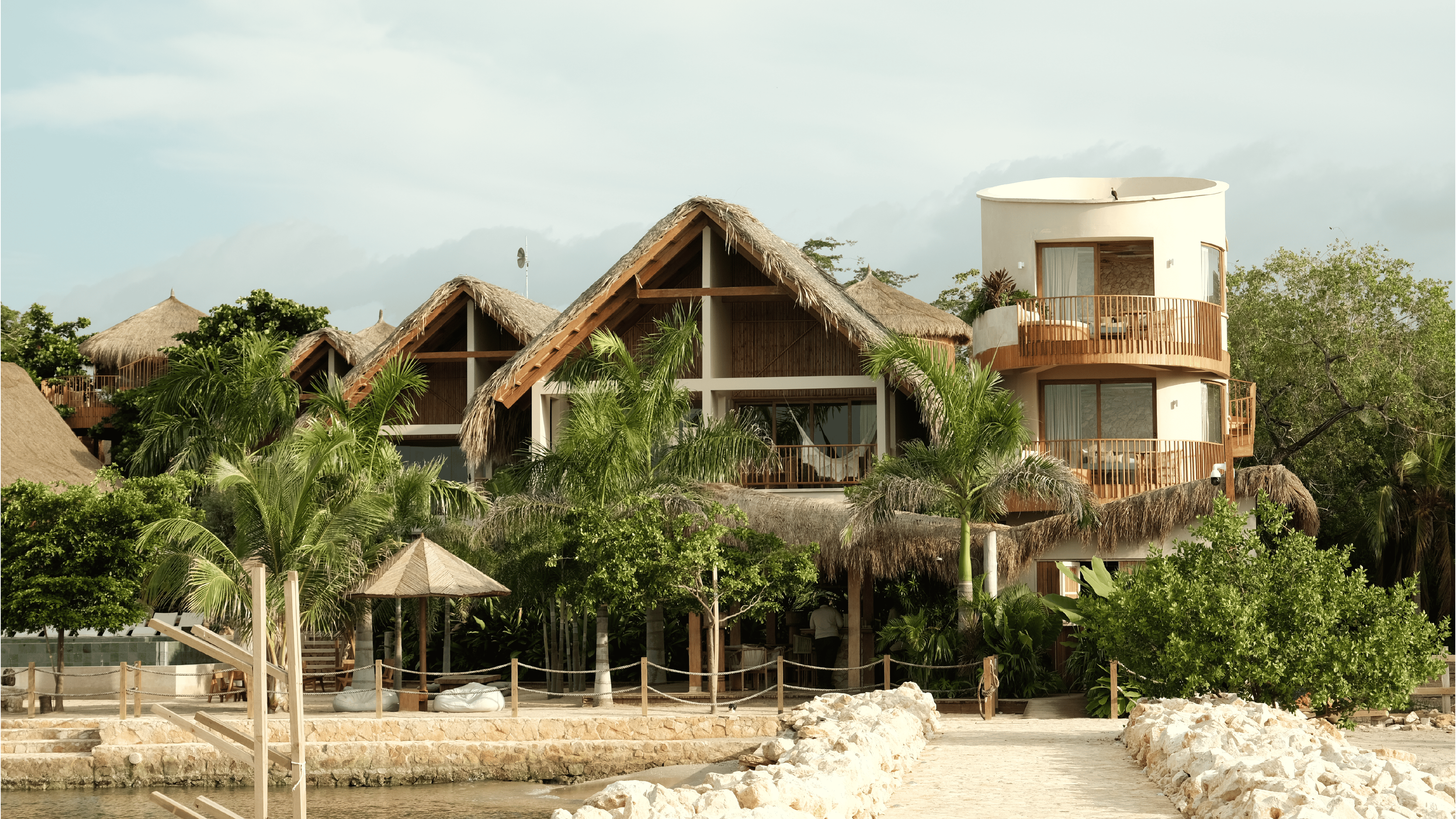 Beachfront resort with traditional thatched roof villas and lush tropical landscaping in a serene co.
