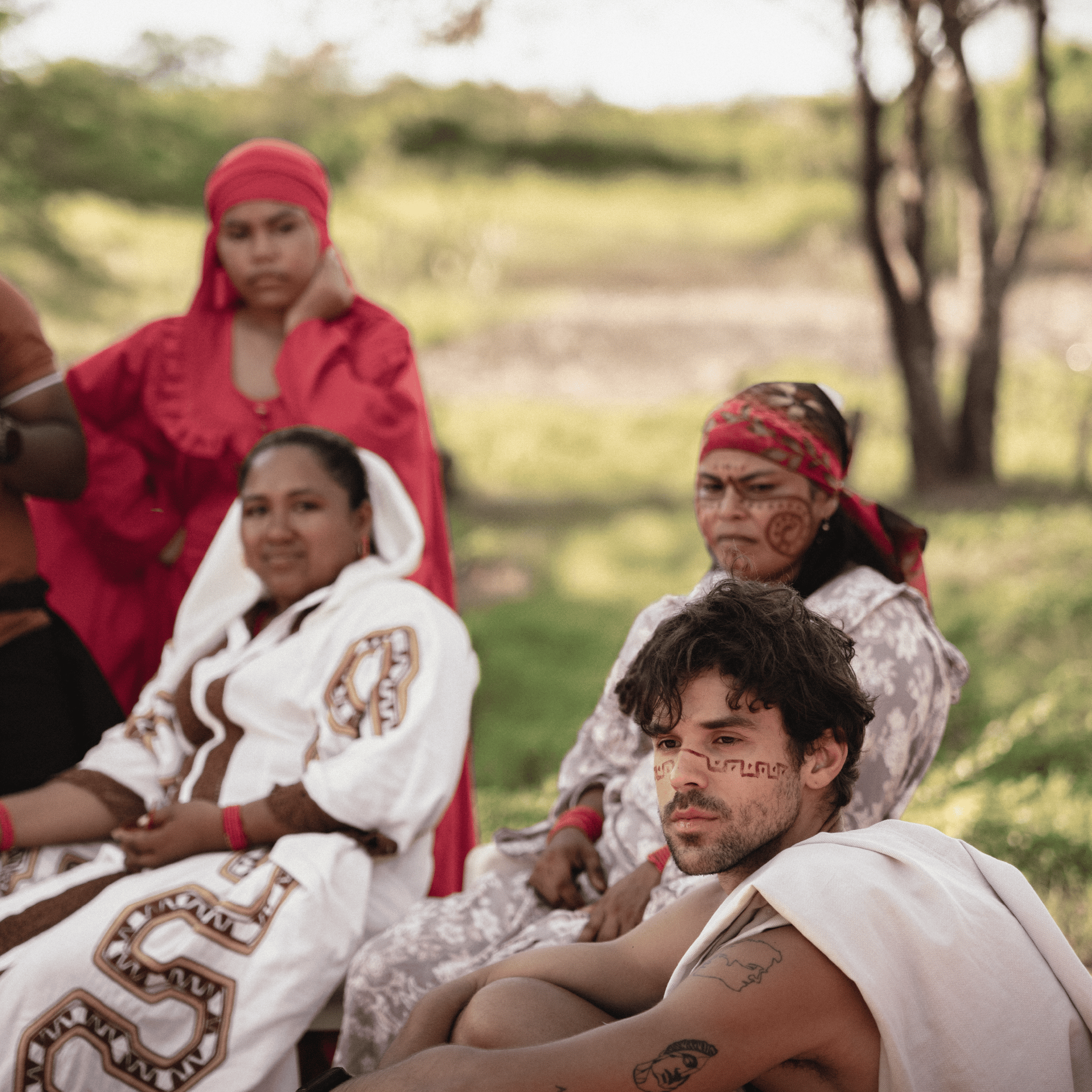 Group of indigenous people in traditional attire outdoors, celebrating cultural heritage.