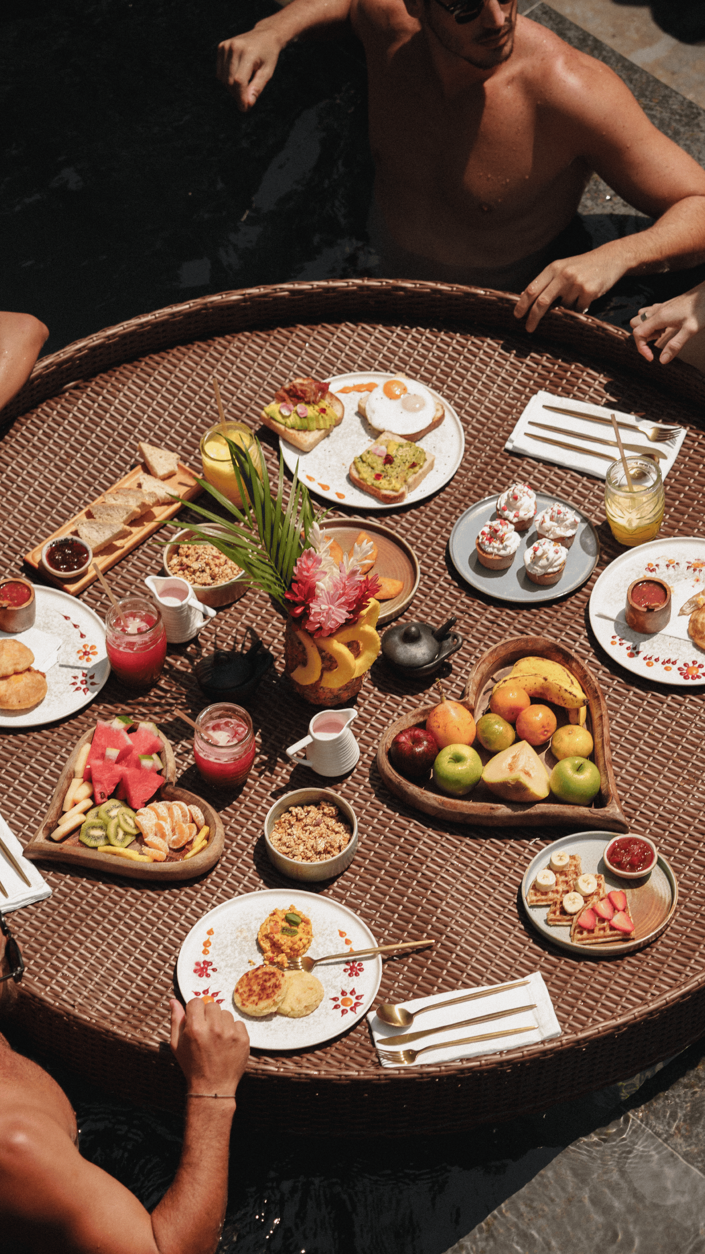 Poolside breakfast with tropical fruits, pastries, and beverages in a luxurious setting.
