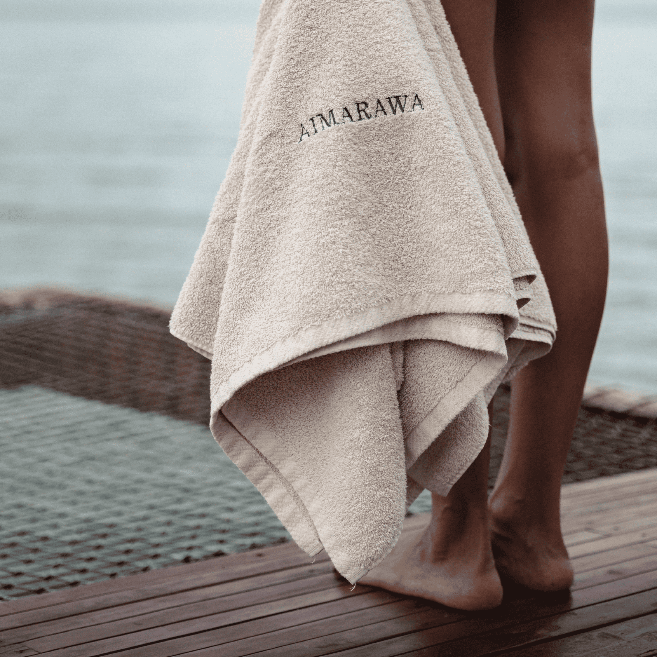Embroidered beach towel featuring "AMARAWA" logo, perfect for seaside relaxation and stylish sunbath.