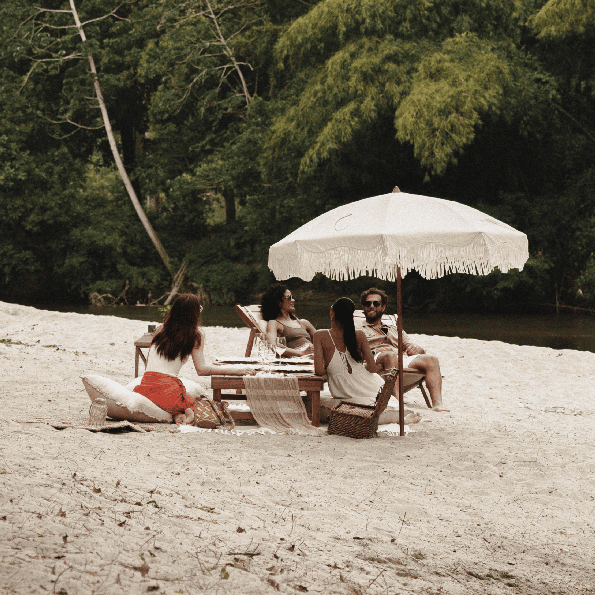 Relaxing beach scene with friends under a white umbrella, enjoying sunny weather and nature.