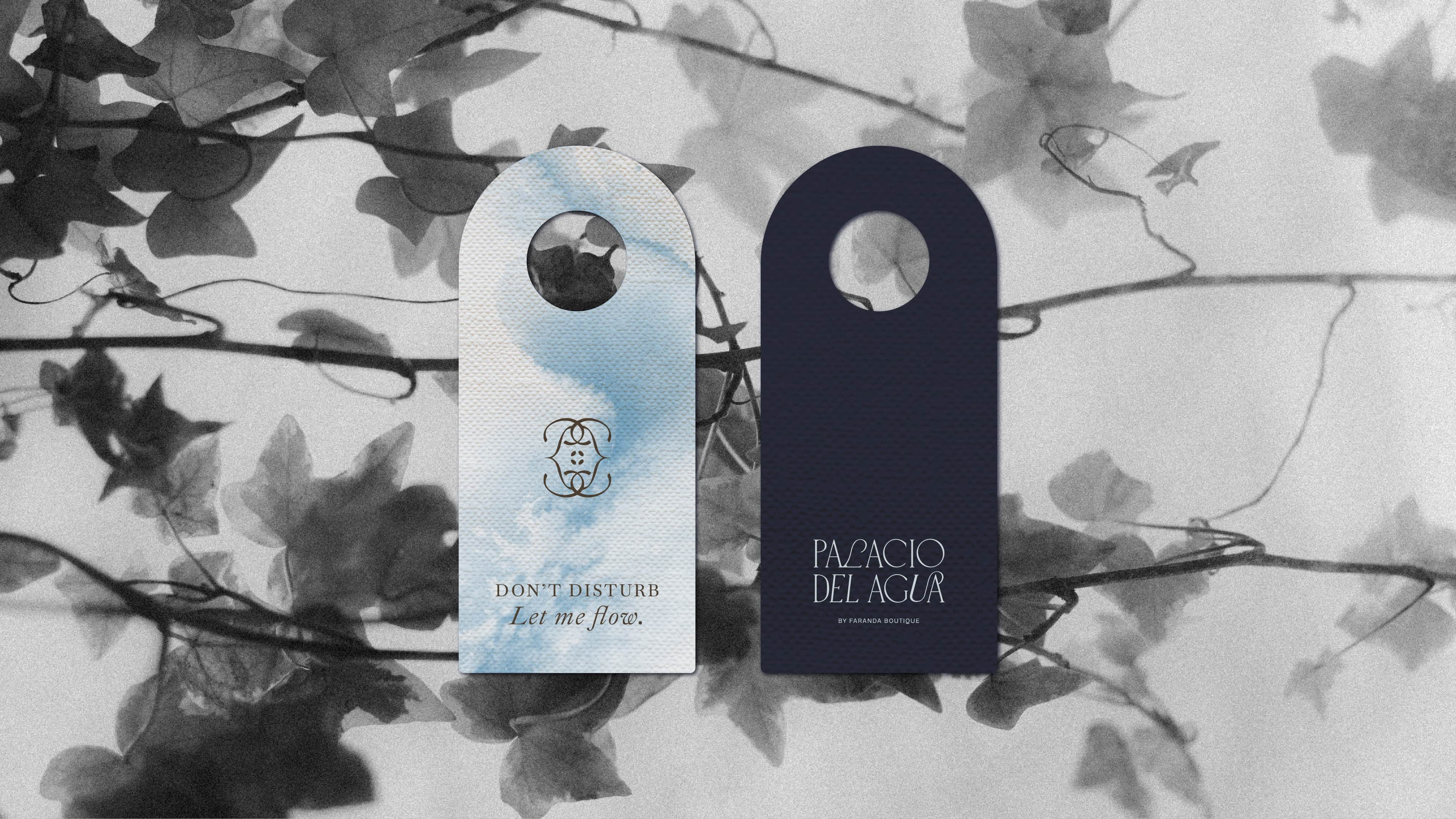 Two decorative tags hanging on a vine with leaves, one with a logo and the other with text.