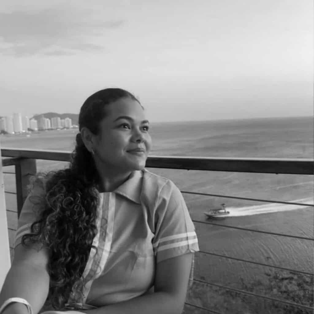Young woman with long curly hair looking at the sea from balcony.