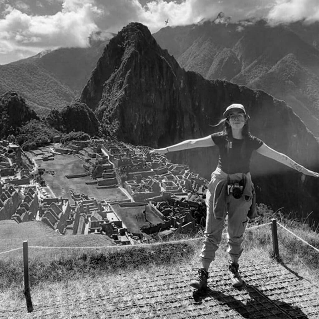 Woman enjoying panoramic view of Machu Picchu and surrounding mountains.