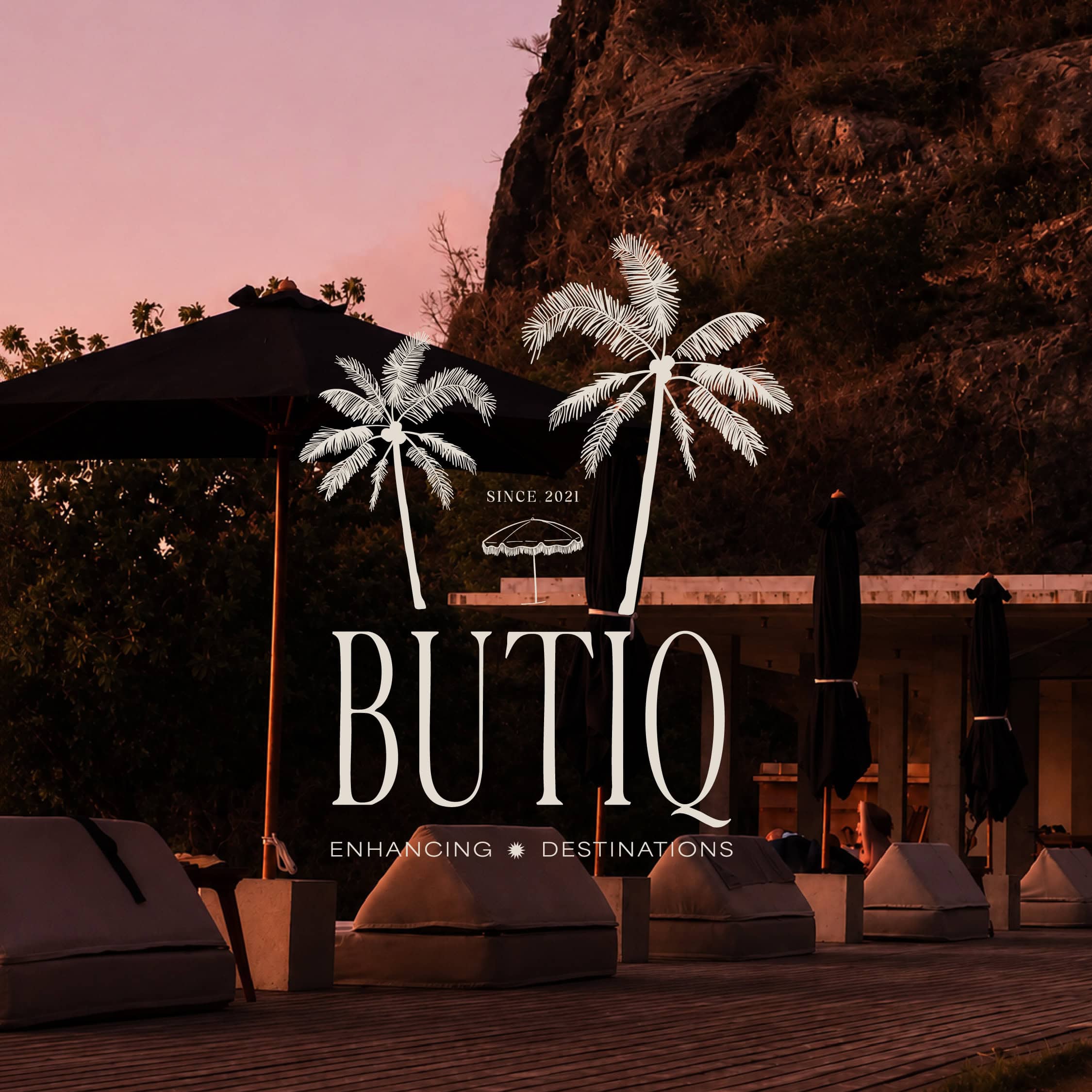 Butiq World logo with palm trees and outdoor seating at sunset.