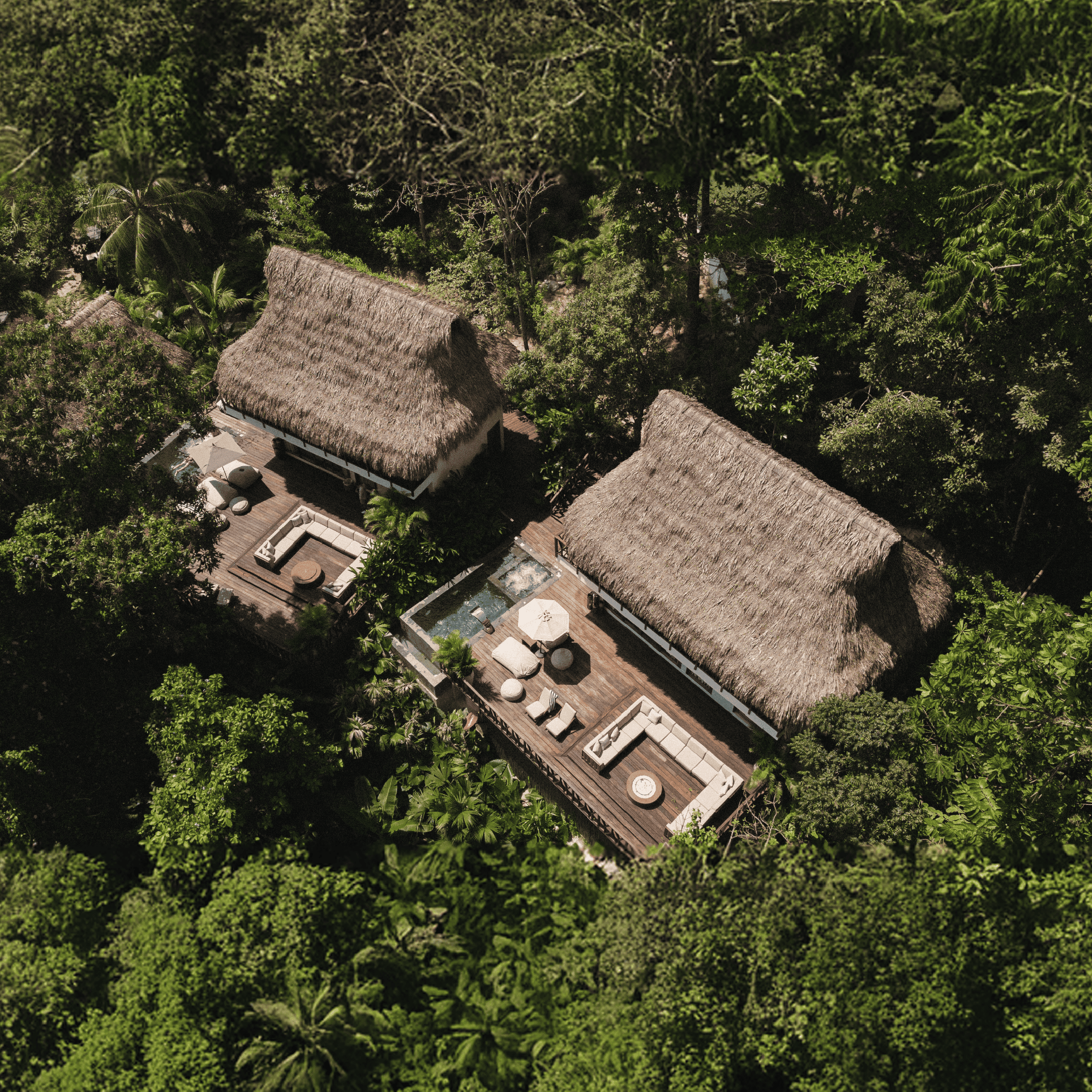 Eco-friendly tropical resort with traditional thatched roofs and outdoor pool, nestled in lush green.