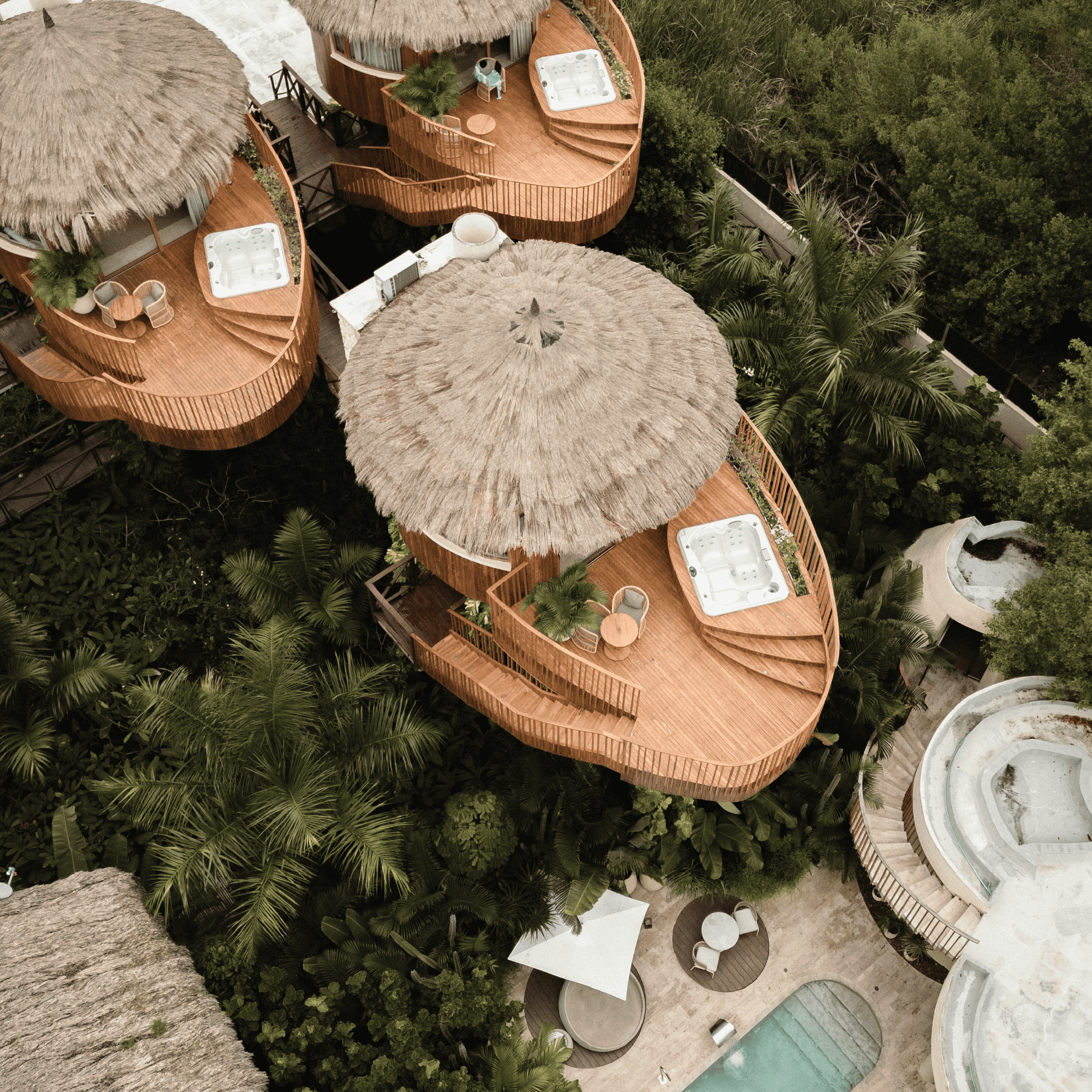 Beachside bungalows featuring private hot tubs and thatched tiki huts, surrounded by lush greenery f.