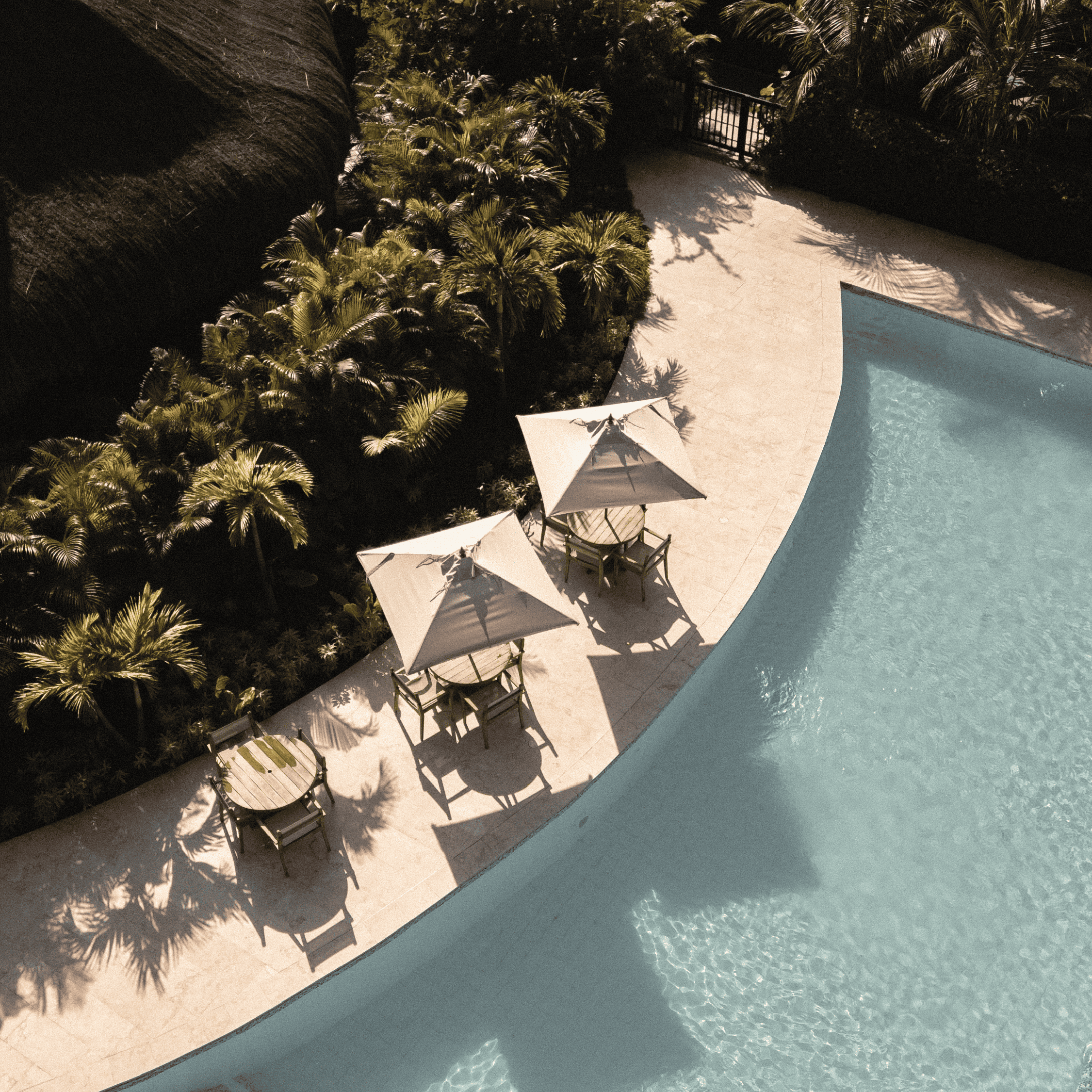 Relaxing poolside area with sun umbrellas and lounge chairs in a tropical setting.