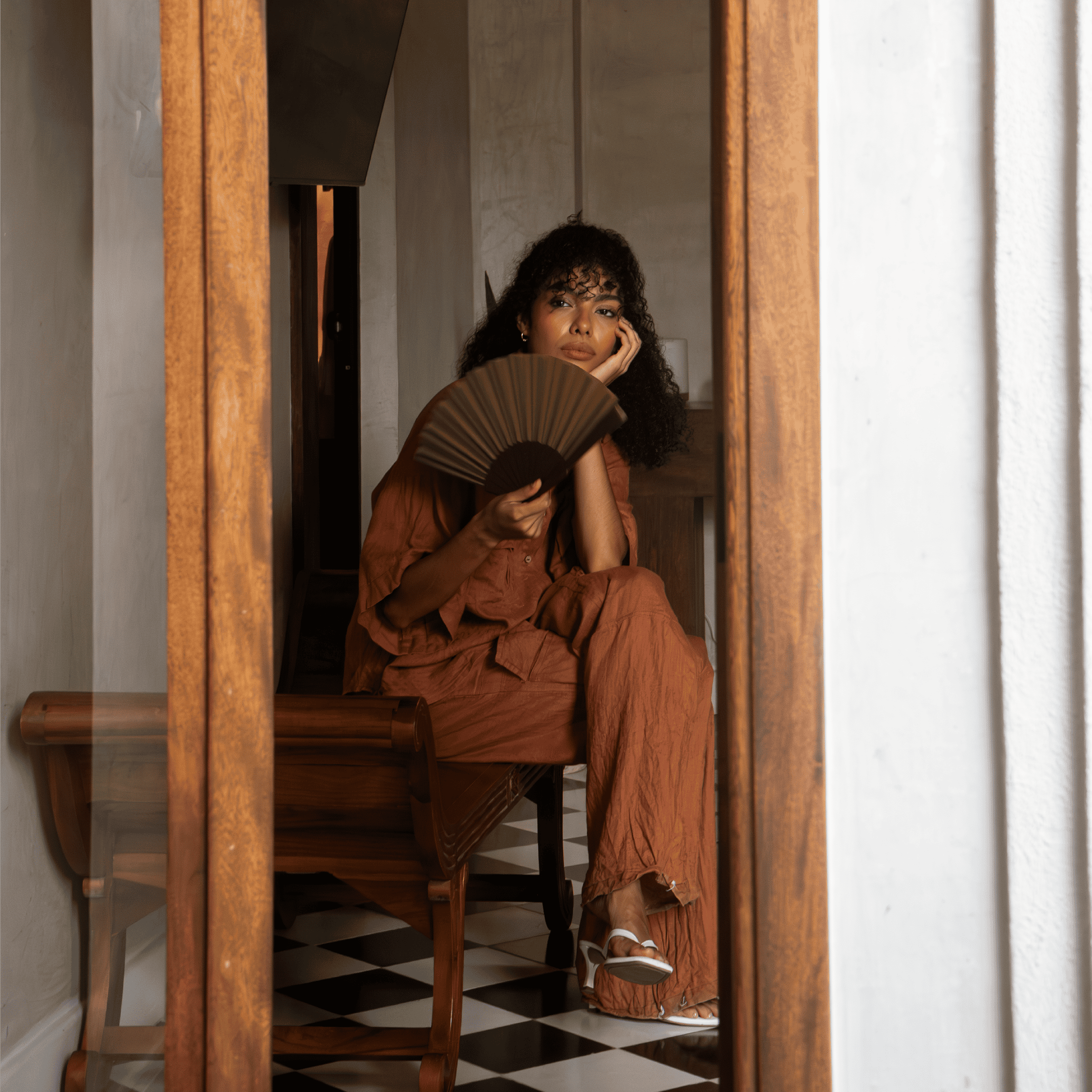 Fashionable woman with a fan sitting in a stylish interior, emphasizing modern lifestyle and eleganc.