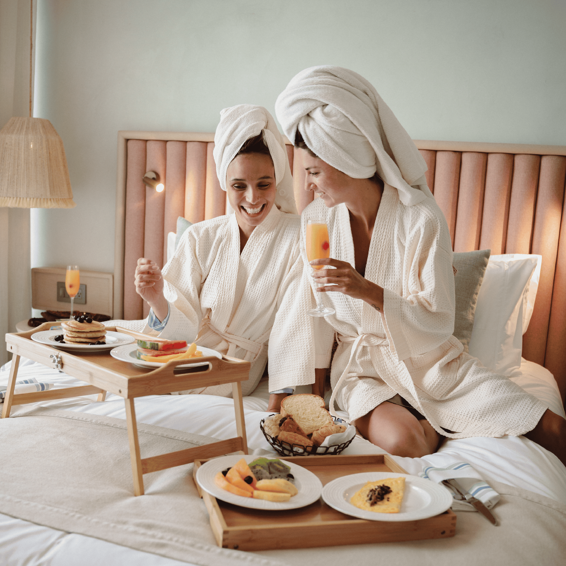Spa friends enjoying breakfast in robes, relaxing in a cozy hotel room.