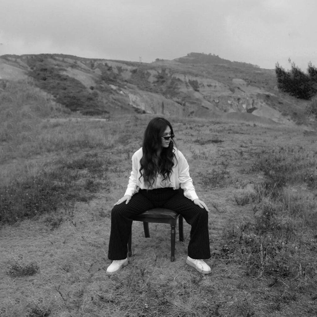 Stylish woman sitting on a chair outdoors in a natural landscape.