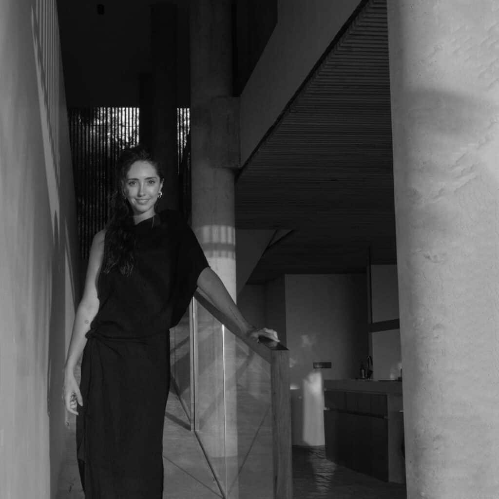 Elegant woman in black dress standing in modern interior space.
