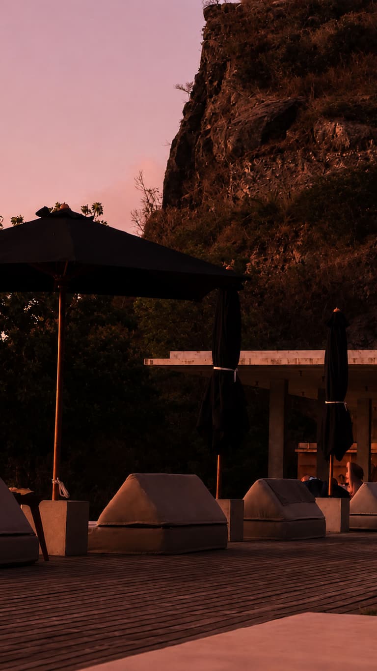 Outdoor seating with umbrellas at Butiq World during sunset.
